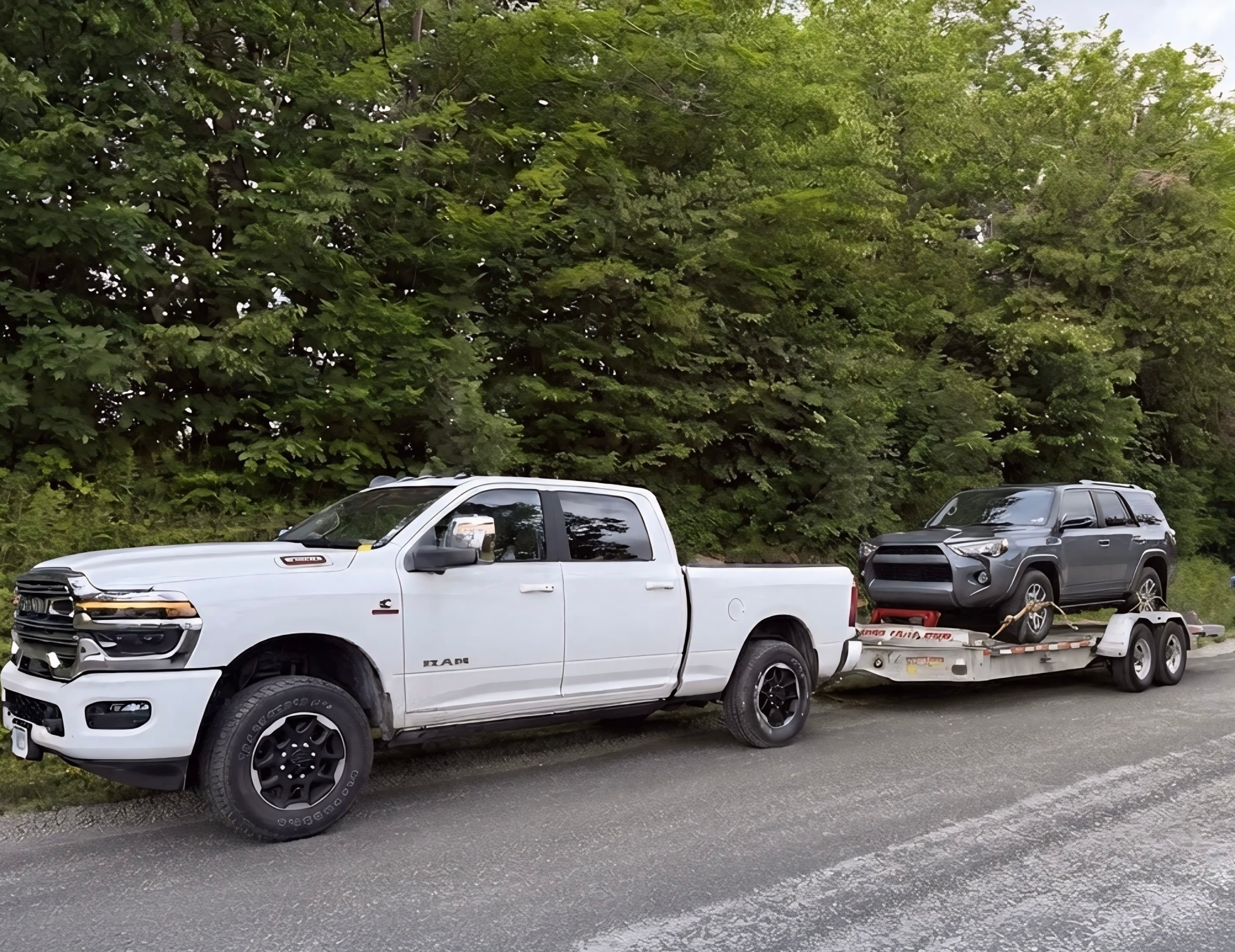 White tow truck hauling a vehicle on a flatbed trailer